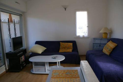un salon avec un canapé bleu et une table dans l'établissement Appartement Duplex 301 Tennis Village 6 Personnes, au Cap d'Agde