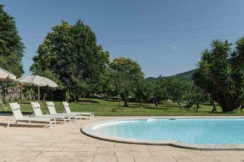 a swimming pool with lounge chairs and an umbrella at Casa Amorim Girão in Fataunços