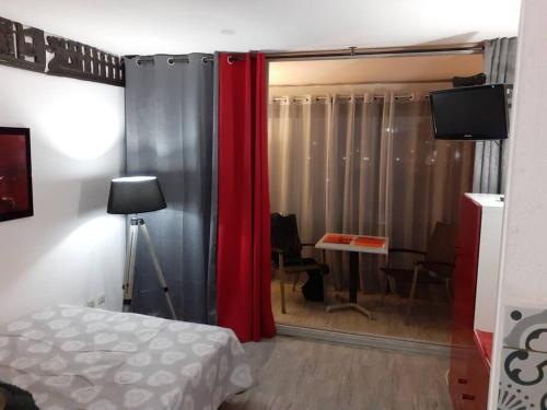 - une chambre avec un rideau rouge, une table et un bureau dans l'établissement Studio 309, Port Vénus au village naturiste, au Cap d'Agde