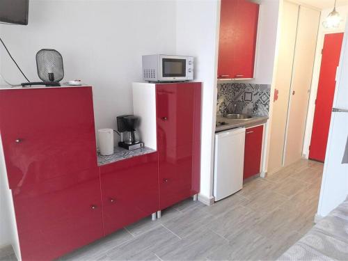 une cuisine avec une armoire rouge et un four micro-ondes. dans l'établissement Studio 309, Port Vénus au village naturiste, au Cap d'Agde