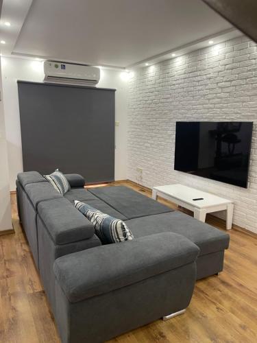 sala de estar con sofá gris y TV de pantalla plana en Maestro Sea - View Apartment, en Lárnaca