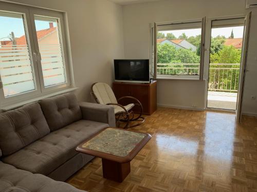 uma sala de estar com um sofá e uma televisão e duas janelas em Apartments Janko em Pakoštane