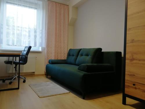 a living room with a green couch and a desk at Apartament nad Węgorapą in Węgorzewo