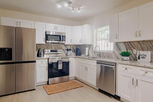 una cocina con armarios blancos y electrodomésticos de acero inoxidable en Cozy 3Bdr home in the heart of Tampa, en Tampa