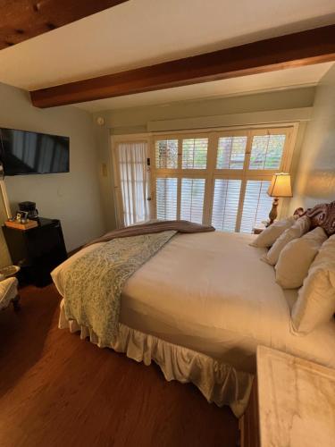 a bedroom with a large white bed with a window at Carmel Garden Inn in Carmel
