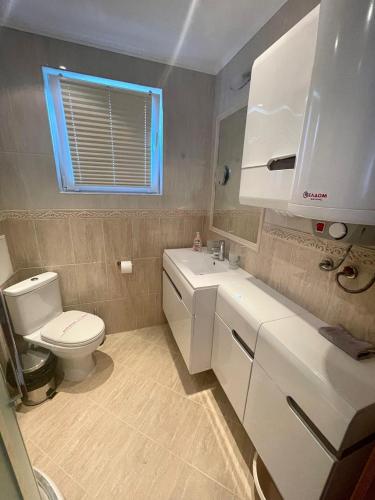 a bathroom with a white toilet and a sink at Byla Sun Day Apartament in Byala