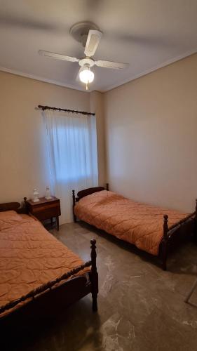 a bedroom with two beds and a ceiling fan at Διαμέρισμα με θέα στη θάλασσα στα Λουτρά Ωραίας Ελένης in Loutra Oraias Elenis