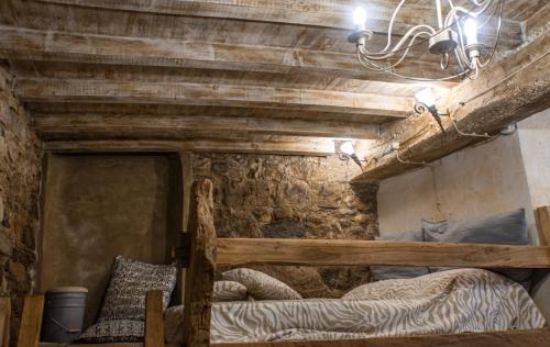 1 dormitorio con cama y pared de piedra en IL NIDO DI MATILDE _monolocale design sul fiume_, en Rossena