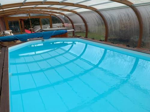 a large swimming pool in a dome with blue water at Villa Jura, l’écrin à pied entre village et pistes in Foncine-le-Haut