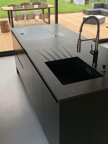 d'un comptoir de cuisine avec évier et d'une terrasse. dans l'établissement Villa Jura, l’écrin à pied entre village et pistes, à Foncine-le-Haut