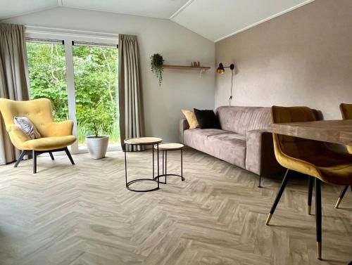 uma sala de estar com um sofá, uma mesa e cadeiras em Landzicht Natuur Rust en Ruimte em Oosterwolde