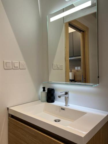 une salle de bain avec un lavabo et un miroir dans l'établissement L’esplanade du lac, à Gérardmer
