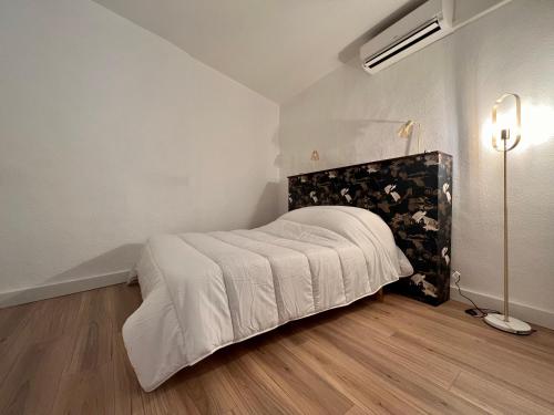 a white bedroom with a bed and a lamp at Collioure, centre ville, joli T2 in Collioure