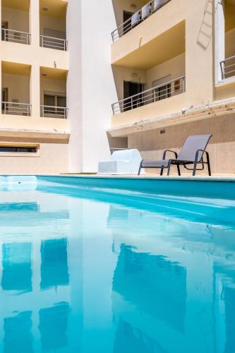 a swimming pool with two chairs next to a building at Lua do Mar - T2 - Piscina - Fte ao Mar- Central in Nazaré