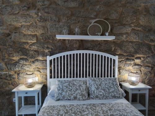 a bedroom with a white bed and two night stands at Apartamentos & Rooms Santiaguiño in Padrón