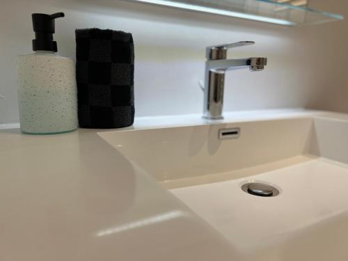 a sink with a soap dispenser and a bottle on it at L’esplanade du lac in Gérardmer