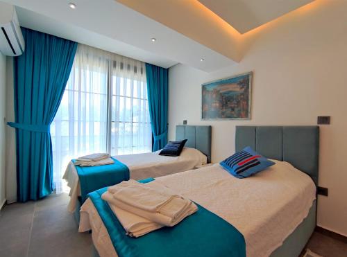 1 dormitorio con 2 camas y una ventana con cortinas azules en villa nerit, en Fethiye