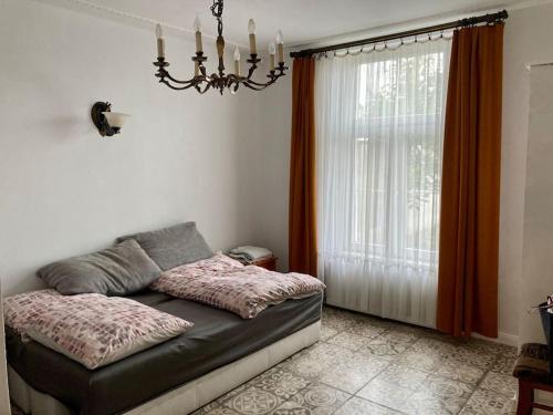 1 dormitorio con 1 cama con lámpara de araña y ventana en Apartament Raszyn za grosze 