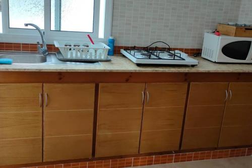 a kitchen counter with a sink and a microwave at joli appartement de vacances in Tétouan