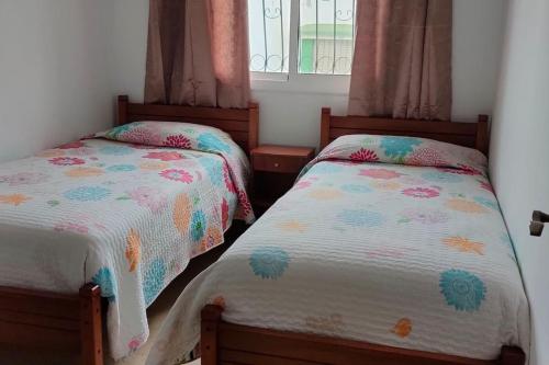 a bedroom with two beds and a window at joli appartement de vacances in Tétouan