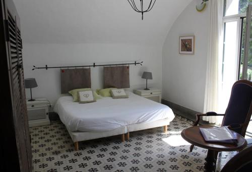 a bedroom with a white bed and a chair at Domaine de la Carrière in Sumène