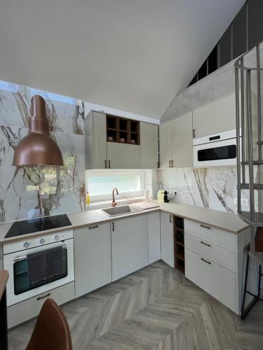 a kitchen with white cabinets and a sink at Beige Villa Balatonkenese in Balatonkenese