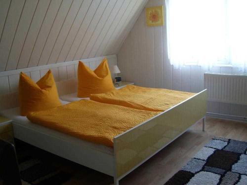 a bed with orange sheets and pillows in a room at Ferienhaus Plau am See SEE 4231 in Plau am See