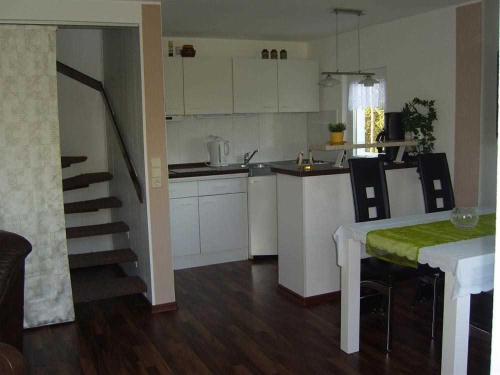 a kitchen with white cabinets and a table and a kitchen with a staircase at Ferienhaus Plau am See SEE 4231 in Plau am See