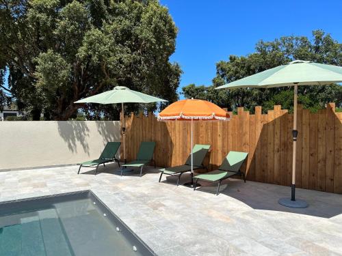 two umbrellas and chairs next to a swimming pool at Résidence Petra Paolina in Folelli