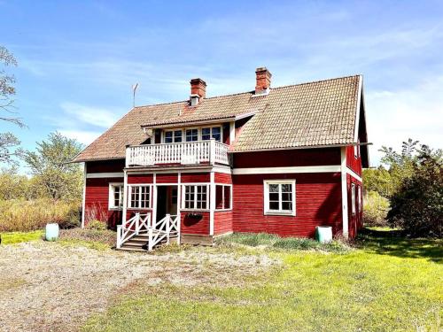 a red house with a balcony on a field at Sjönära lantgård i Bergslagen in Skinnskatteberg