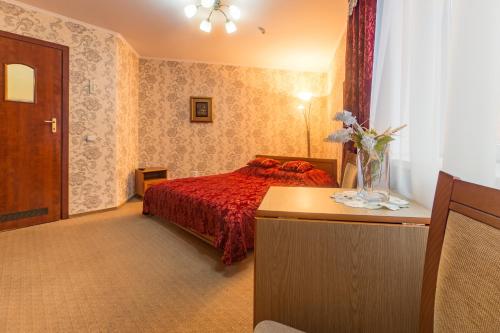 Hotel Premyer في تريسكوفيتس: غرفة نوم بسرير ولحاف احمر وطاولة