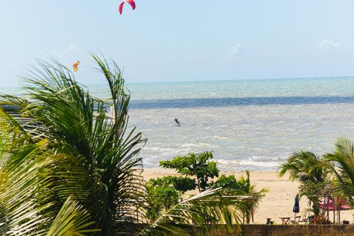 a beach with palm trees and a person parasailing in the ocean at Pousada Sitio Phoenix in Prea
