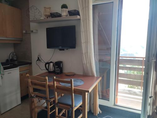 a kitchen with a table with two chairs and a television at Le Cow'sy 1800 in Les Deux Alpes