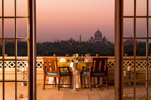 a table with chairs and a view of the taj mahal at The Oberoi Amarvilas Agra in Agra