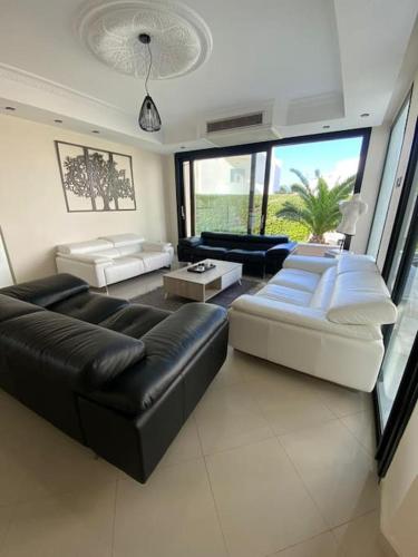 uma sala de estar com um sofá preto e mobiliário branco em La Villa 91 em Monastir