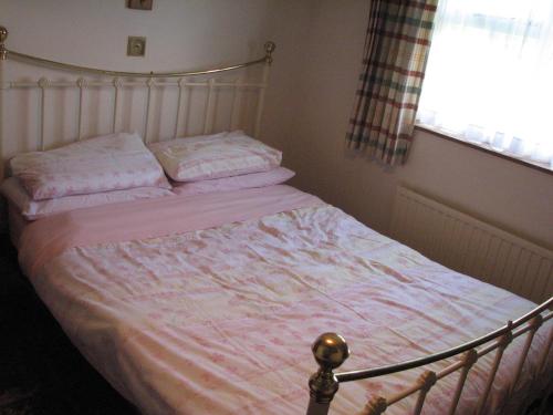 a bedroom with a bed with pink sheets and a window at Church Cottage in Bude