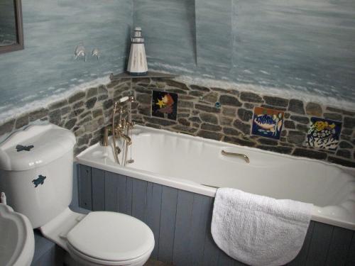 a bathroom with a toilet and a bath tub with a sink at Church Cottage in Bude