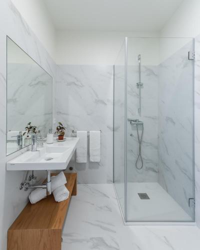 a white bathroom with a shower and a sink at Casa Amorim Girão in Fataunços