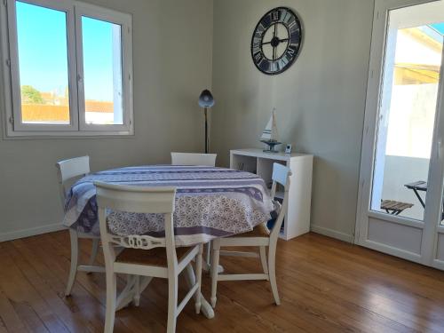 a dining room with a table and chairs and a clock at Sable et Soleil in Royan