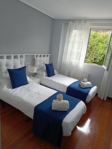 a bedroom with two beds with blue and white sheets at Paraíso Soleado: Piso con Terraza, Piscina y Garaje a 5 min de Playa in Castro-Urdiales