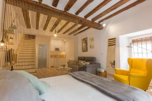 a bedroom with a bed and a yellow chair at DuermeCuenca in Cuenca