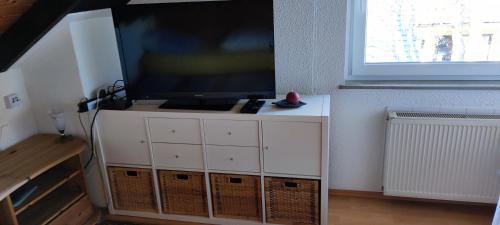 TV de pantalla plana en la parte superior de un armario blanco en Ferienwohnung Gläser, en Hilchenbach