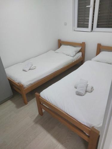 two beds in a room with white sheets at Ranč Andrić in Bajina Bašta