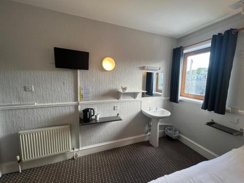 baño con lavabo, cama y ventana en Lost Guest House Aberdeen, en Aberdeen