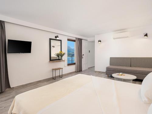 a white living room with a couch and a tv at Porto Kaza in Sitia