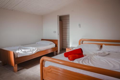 - une chambre avec 2 lits et un oreiller rouge dans l'établissement Plazhi Gjeneralit - Small Cabins - Bungalows - Apartaments - Villas - Suite, à Kavajë