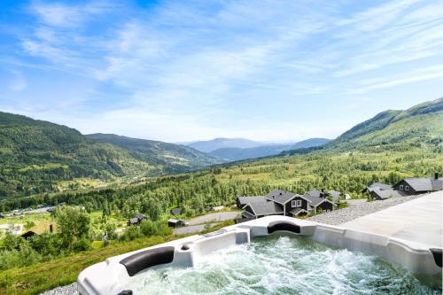 a hot tub in the middle of a valley with mountains at The Panorama Retreat - Rindabotn Cabin in Sogndal