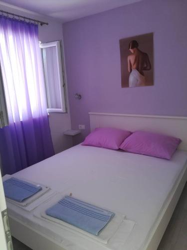 a bedroom with a white bed with pink pillows at Apartman Čarija 2 in Trogir