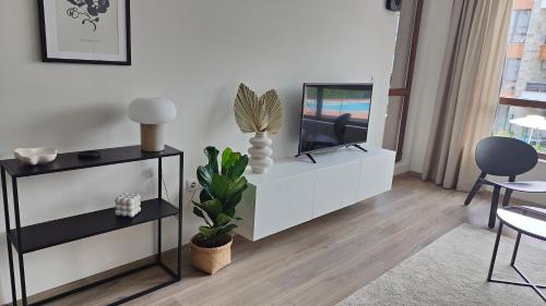 ein Wohnzimmer mit einem TV auf einem weißen Schrank in der Unterkunft Beachfront Apartments, Sarafovo in Burgas City