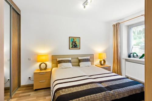 a bedroom with a bed with two lamps and a window at Large private apartment with garden view, terrace and free parking in Bratislava